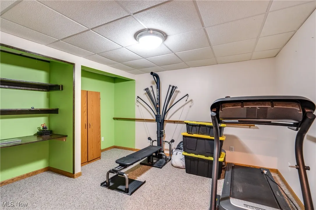 Exercise room with a paneled ceiling and light carpet