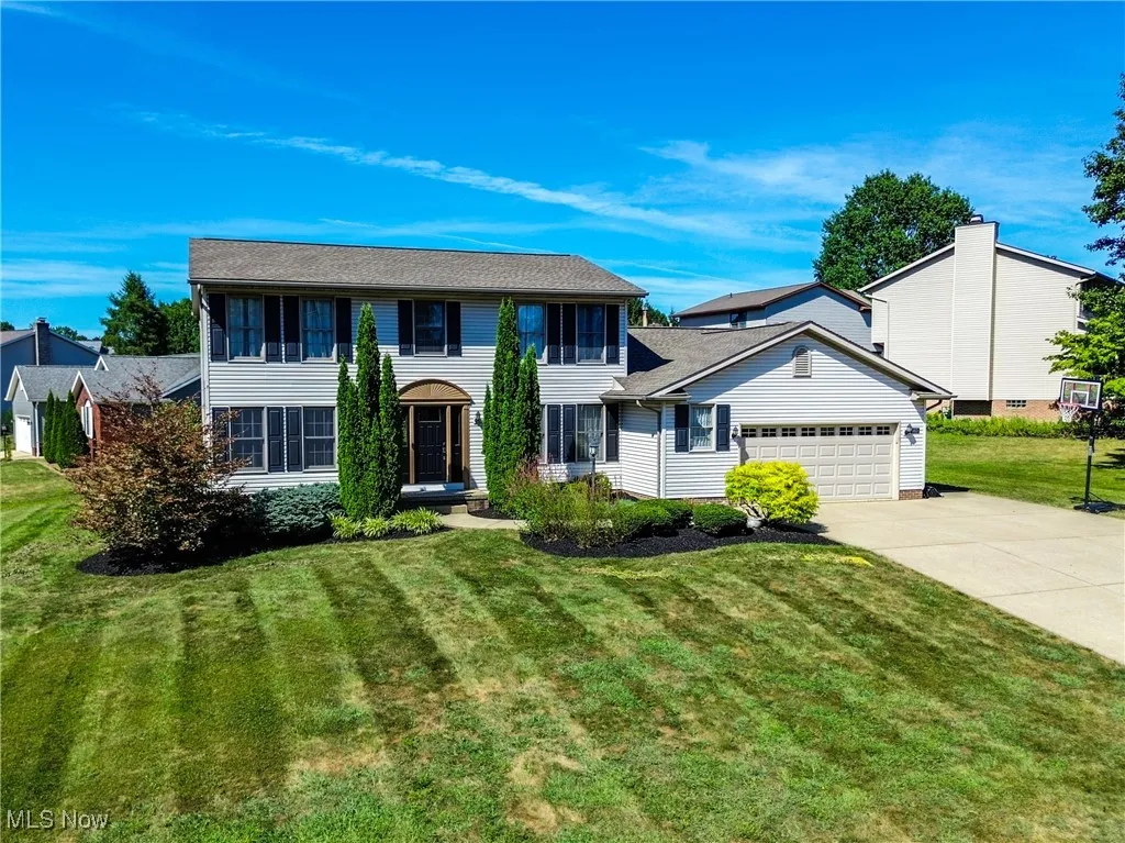 Colonial-style house featuring a front yard, driveway, and an attached garage