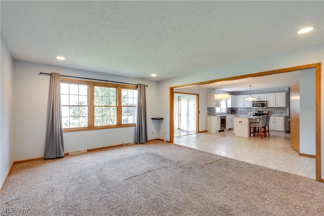 Unfurnished living room with light carpet, recessed lighting, and a textured ceiling