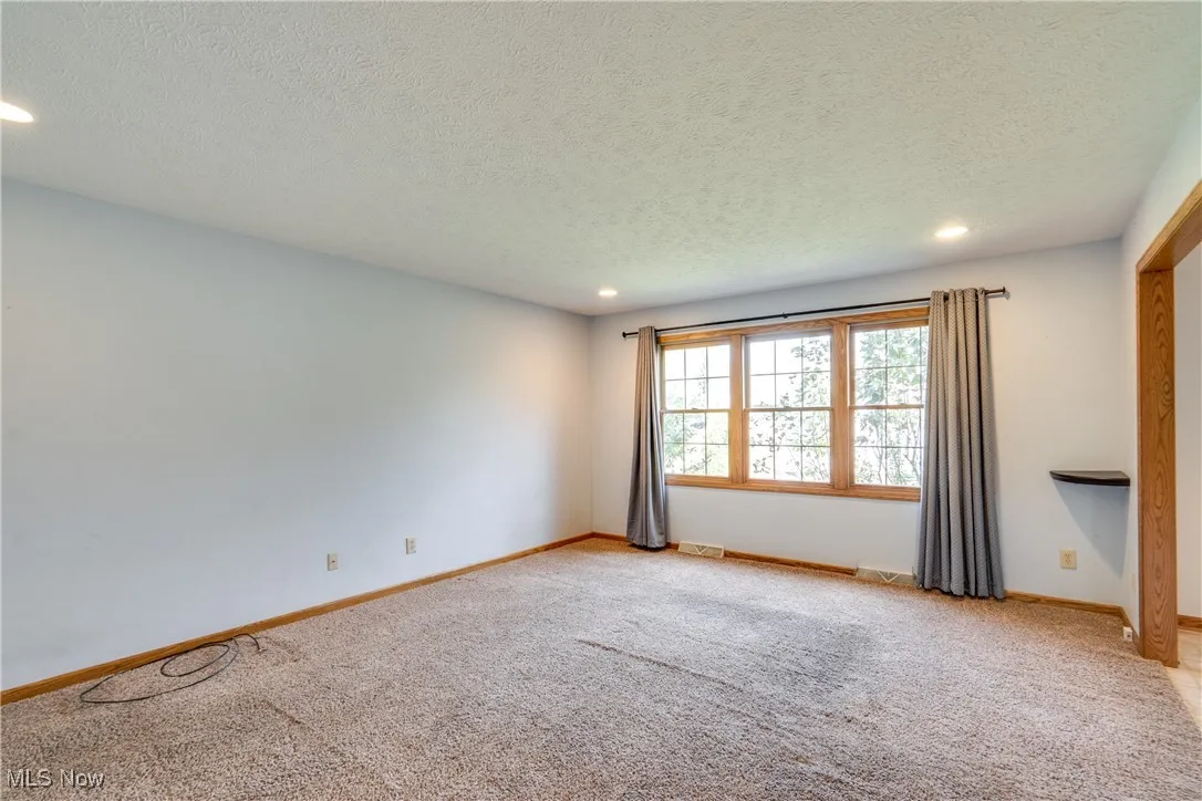 Empty room with recessed lighting, light carpet, and a textured ceiling