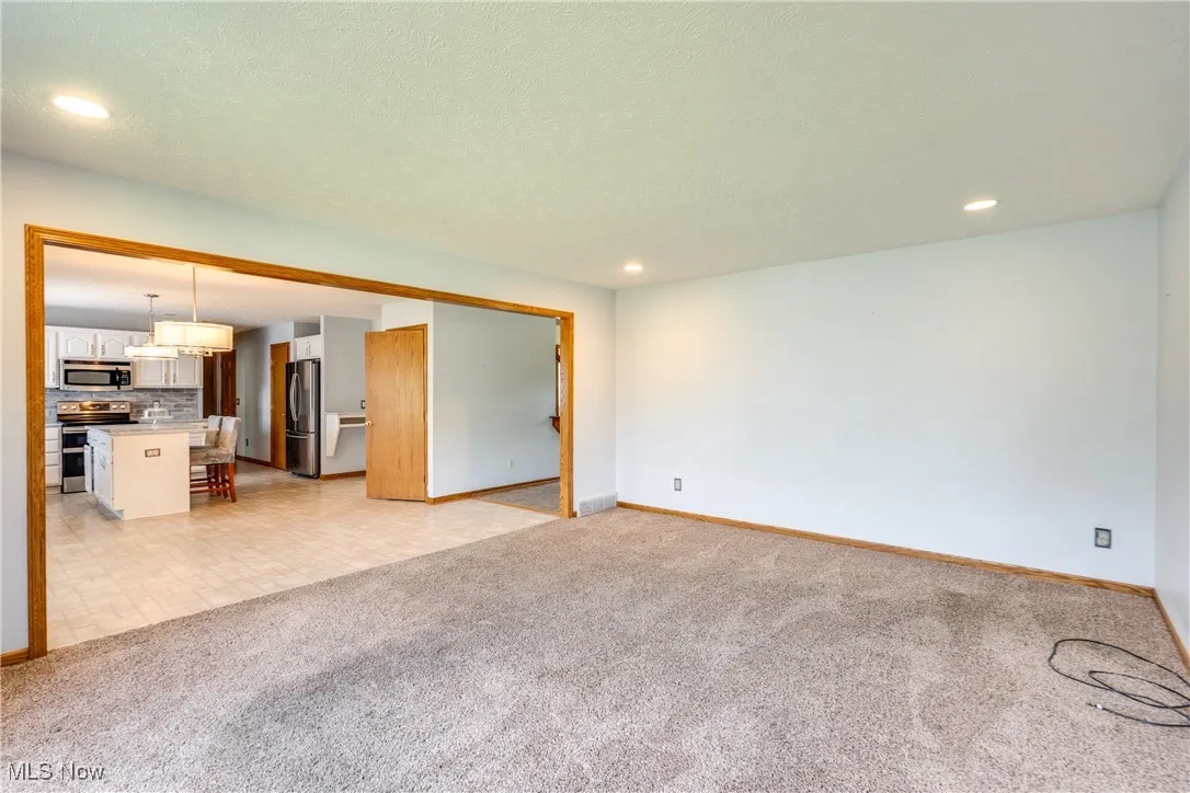 Unfurnished living room featuring light colored carpet, recessed lighting, light tile patterned floors, and a textured ceiling