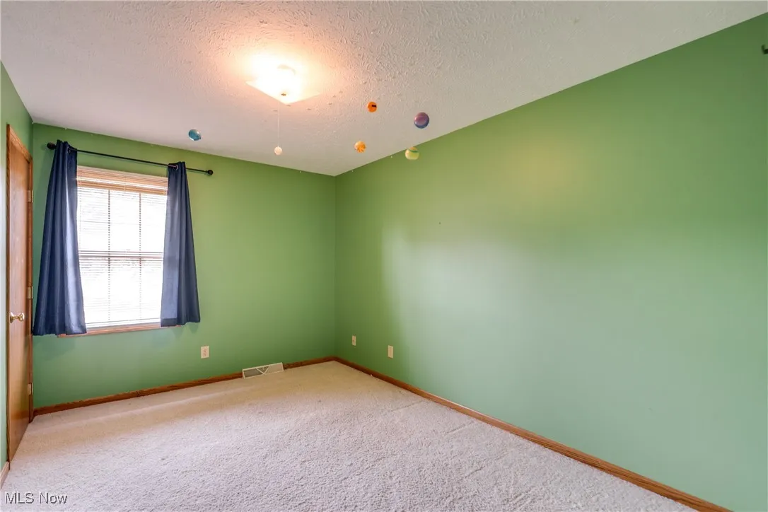 Empty room with carpet floors and a textured ceiling