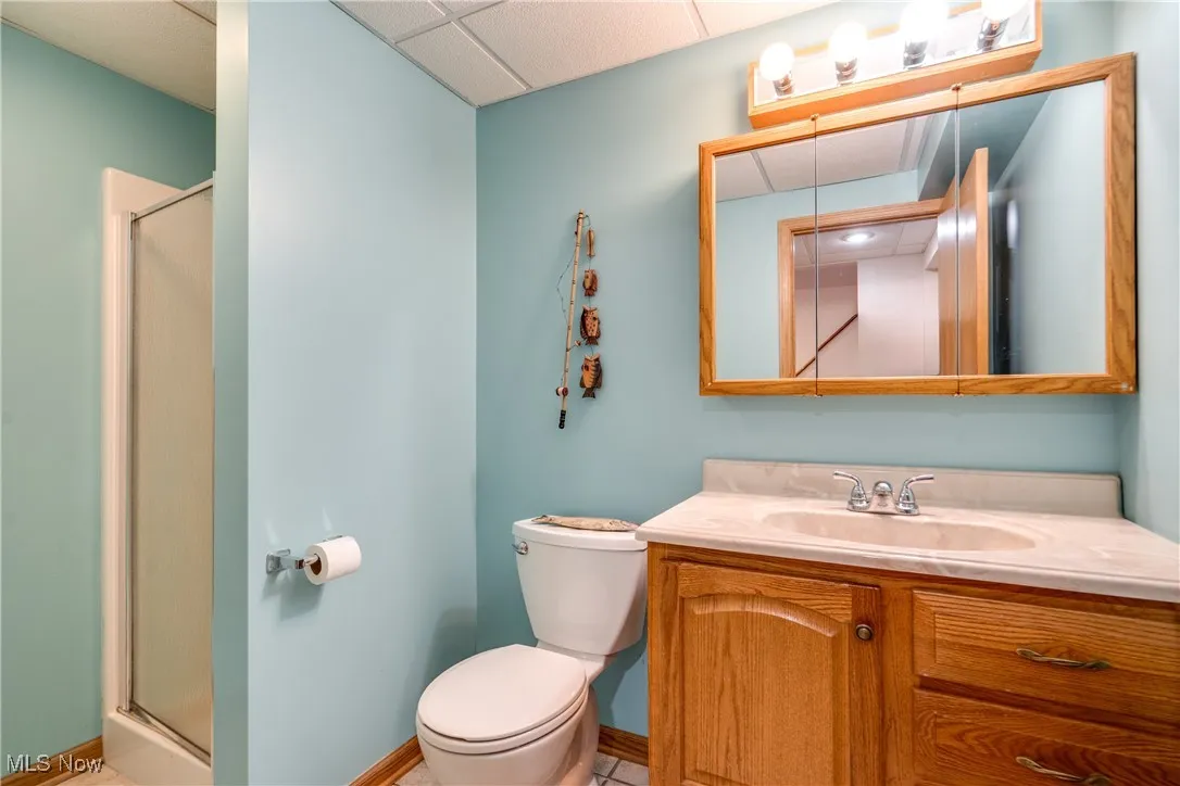 Bathroom with a stall shower, vanity, a paneled ceiling, and tile patterned floors