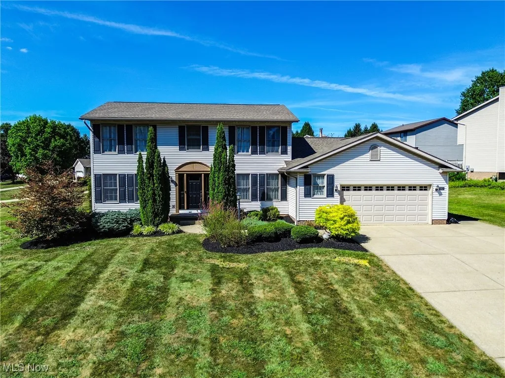 Colonial inspired home featuring an attached garage, a front yard, and driveway