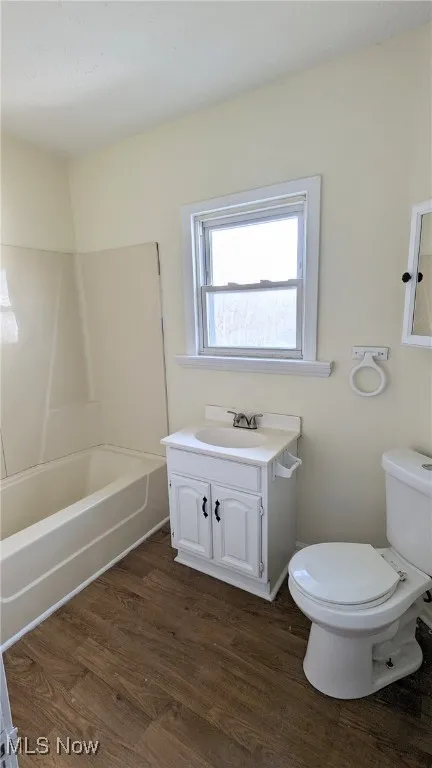 Bathroom featuring dark wood finished floors, vanity, and shower / bathtub combination