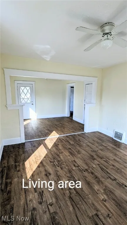 Unfurnished living room with dark wood finished floors and a ceiling fan