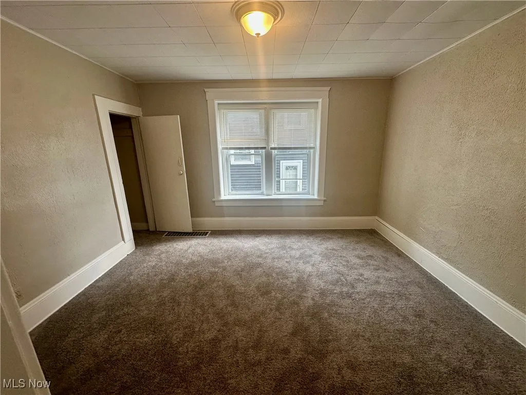 Carpeted spare room with a textured wall