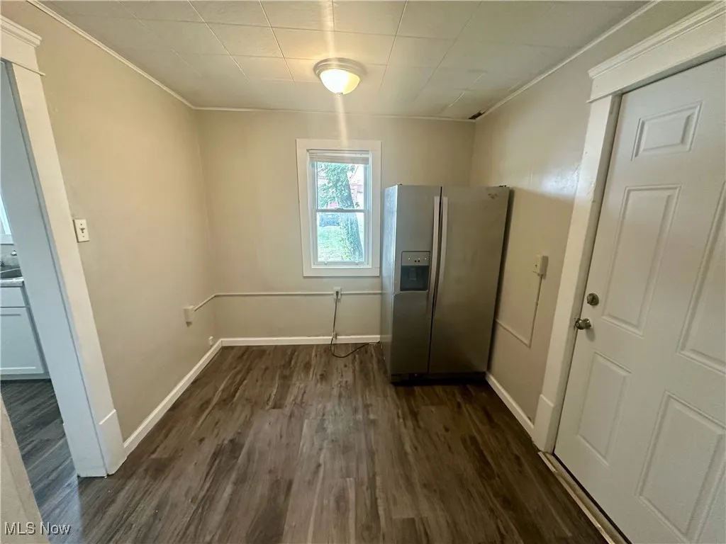Unfurnished dining area featuring dark wood finished floors and ornamental molding