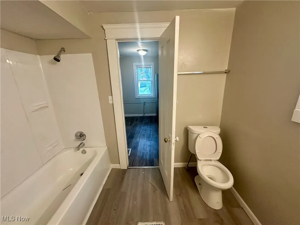 Full bath featuring tub / shower combination and wood finished floors