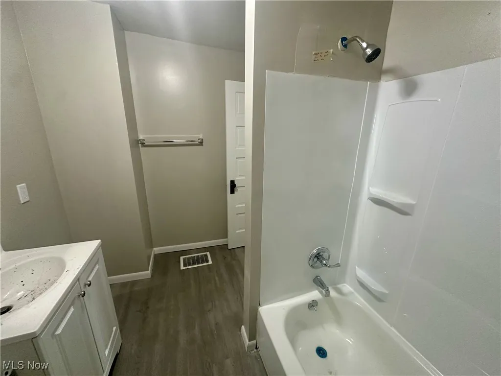 Full bathroom with  shower combination, vanity, and dark wood-style flooring