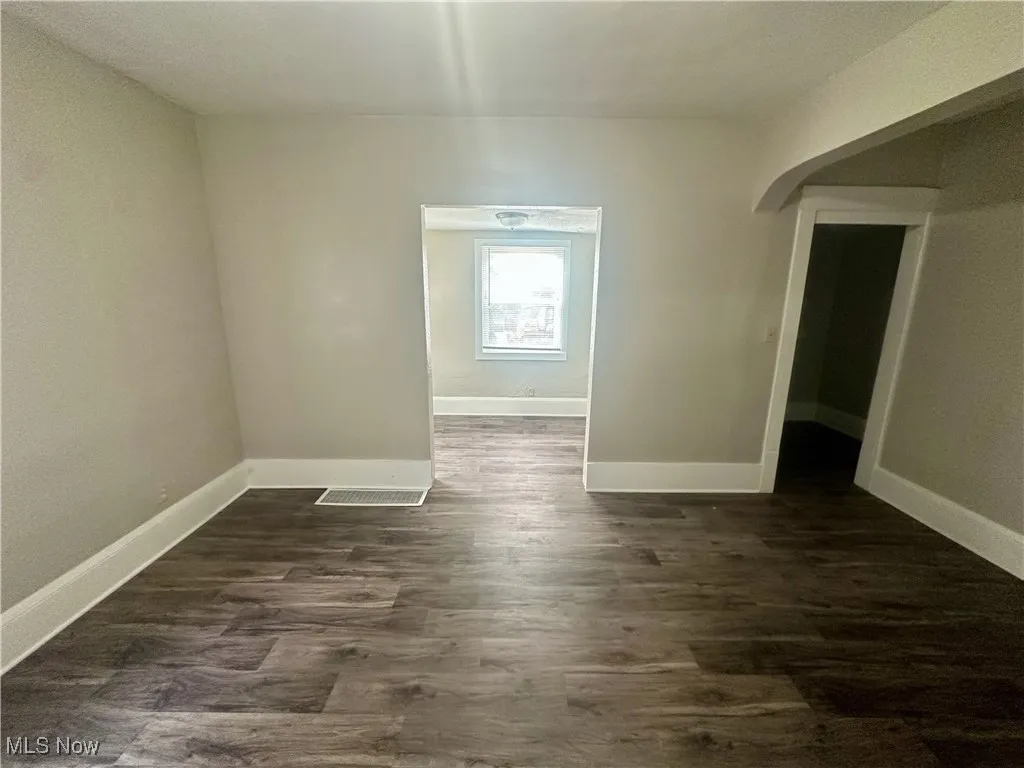 Spare room with dark wood-style flooring and baseboards