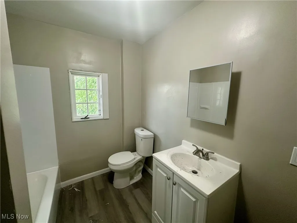 Full bathroom featuring dark wood-type flooring, vanity, and a tub
