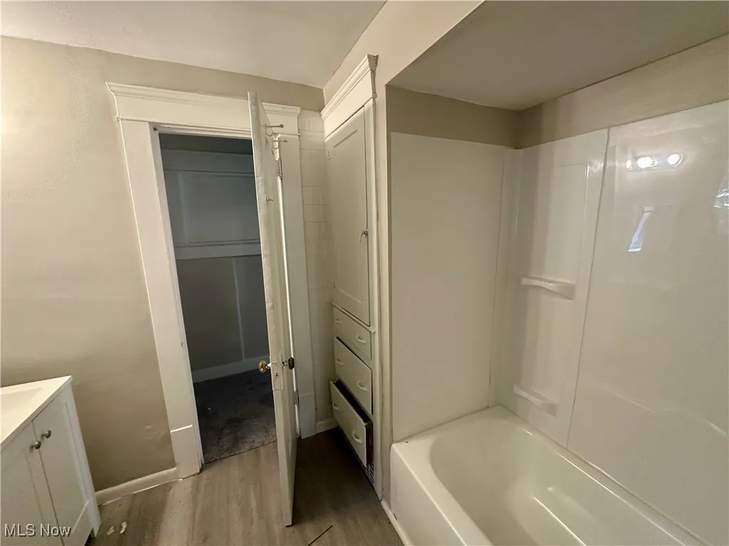 Bathroom featuring vanity, light wood-style floors, and bathing tub / shower combination