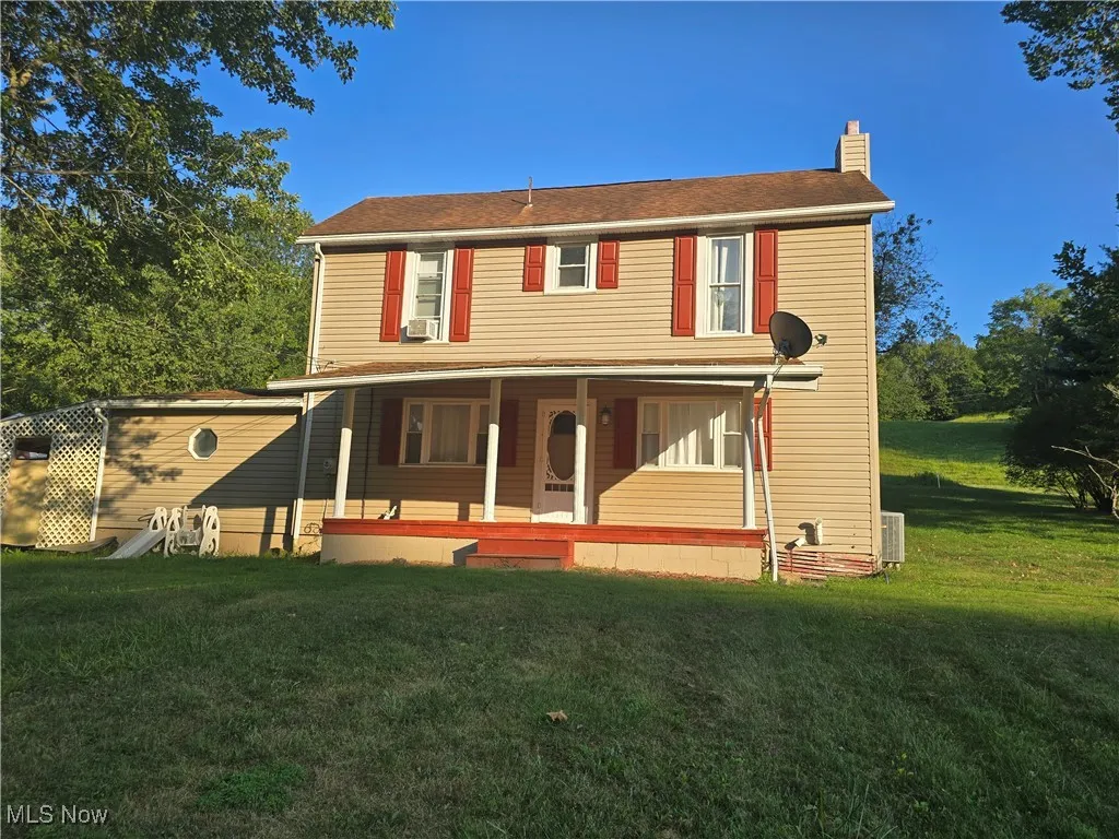 View of front of house with a chimney, a porch, and a front lawn