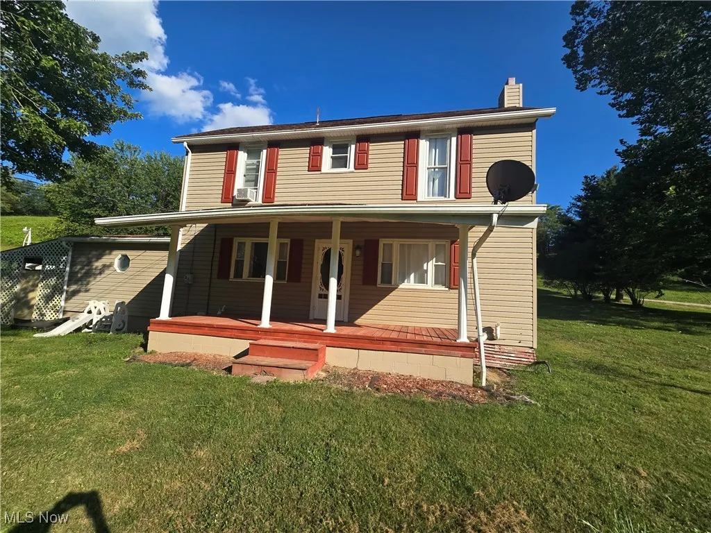 View of front of home featuring a front yard, covered porch, and a chimney