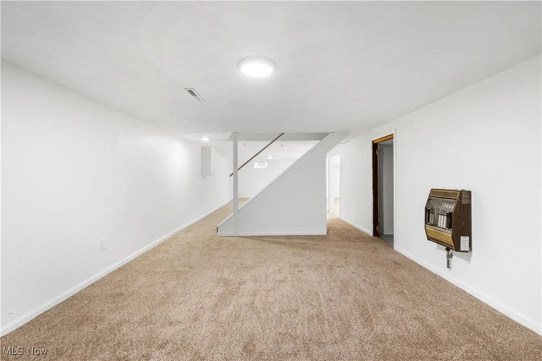 Finished below grade area featuring carpet floors, heating unit, and stairs