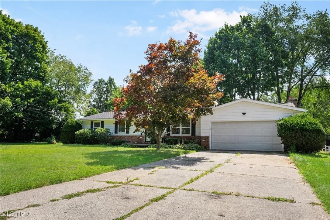 View of front of house with brick siding, a front yard, a garage, and driveway