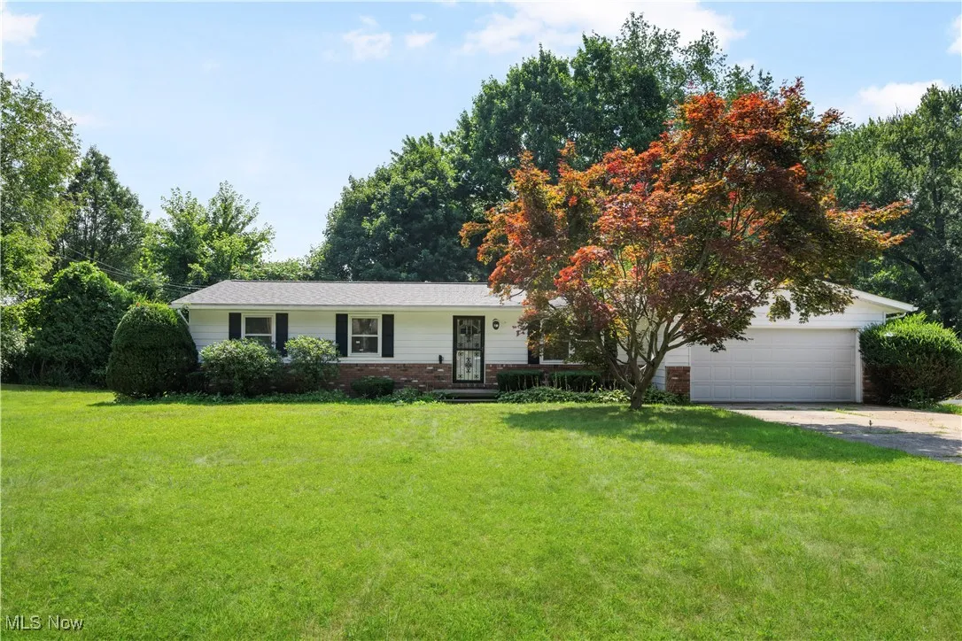 Single story home with brick siding, a garage, a front lawn, and concrete driveway