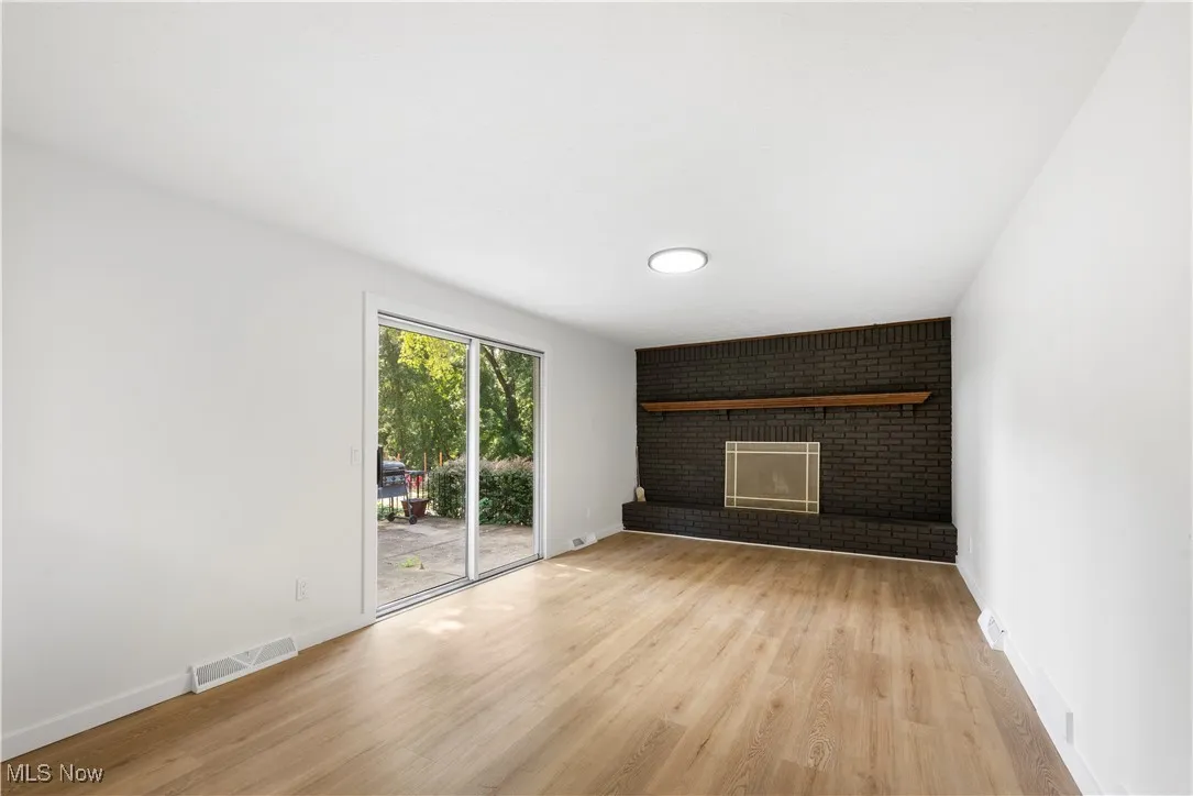 Unfurnished living room featuring light wood-type flooring and a brick fireplace