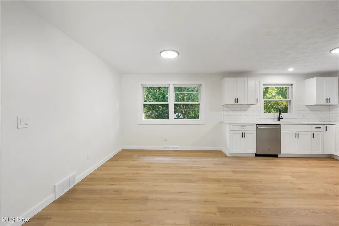 Kitchen with white cabinetry, tasteful backsplash, light wood-style floors, dishwasher, and recessed lighting