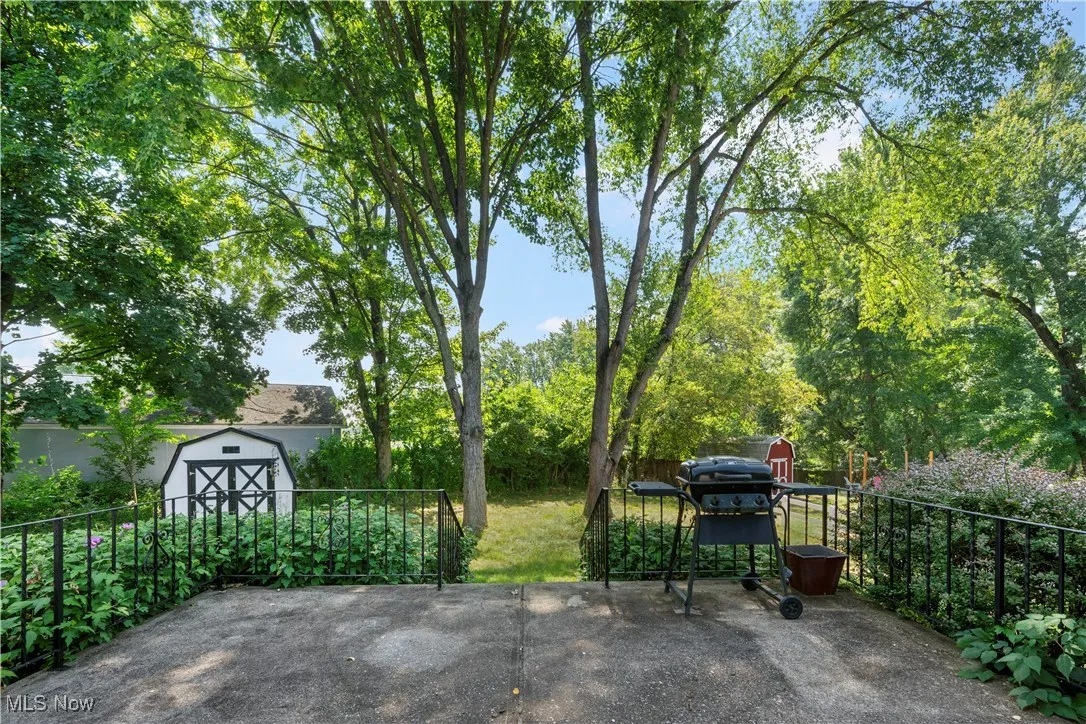 View of patio featuring a storage unit and a grill