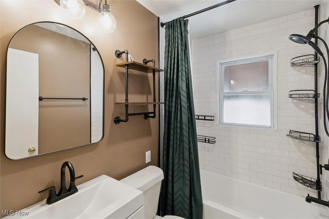 Bathroom featuring shower / bathtub combination with curtain and vanity