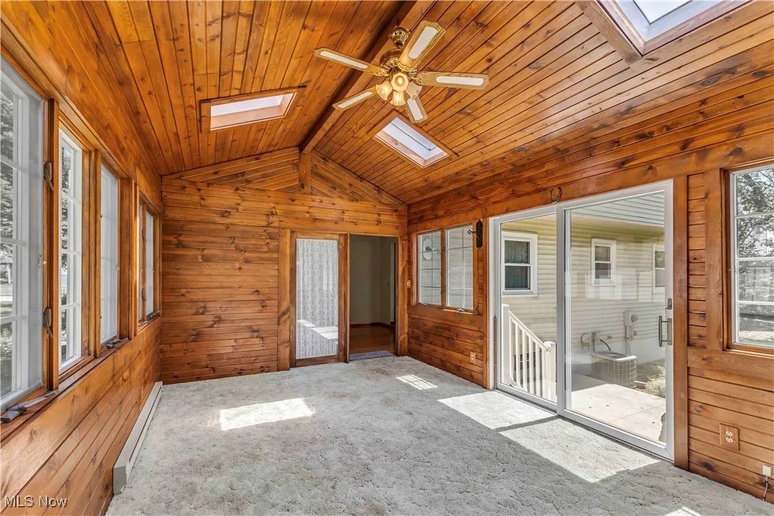 Gorgeous 4 season room with baseboard heat, skylights, plethora of windows, vaulted ceiling, ceiling fan and neutral carpeting.