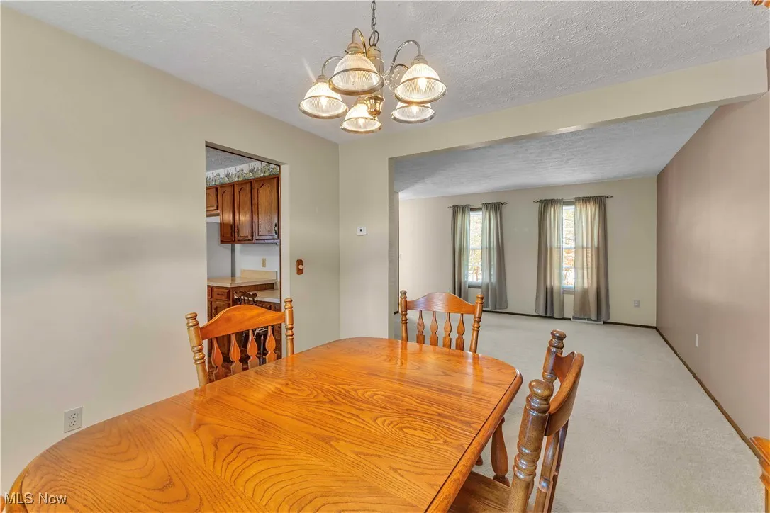 Formal dining room featuring light colored carpeting, neutral paint on the walls and windows letting in the natural light.