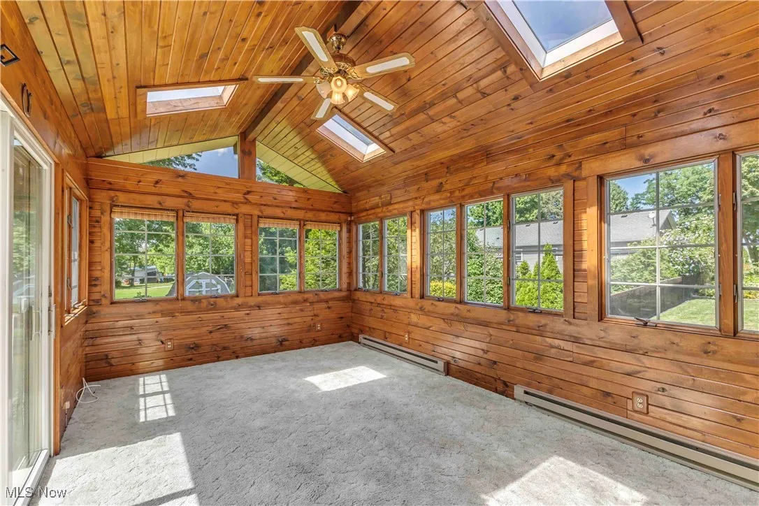 Gorgeous 4 season room with baseboard heat, skylights, plethora of windows, vaulted ceiling, ceiling fan and neutral carpeting.