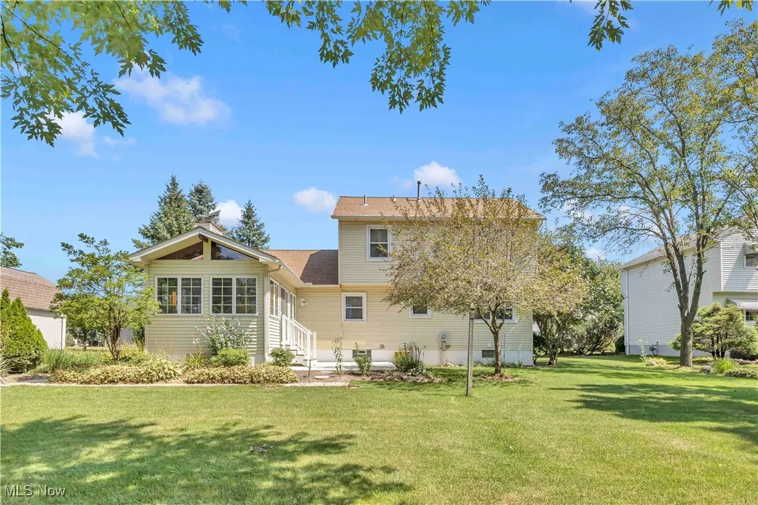 Back of property with a manicured lawn