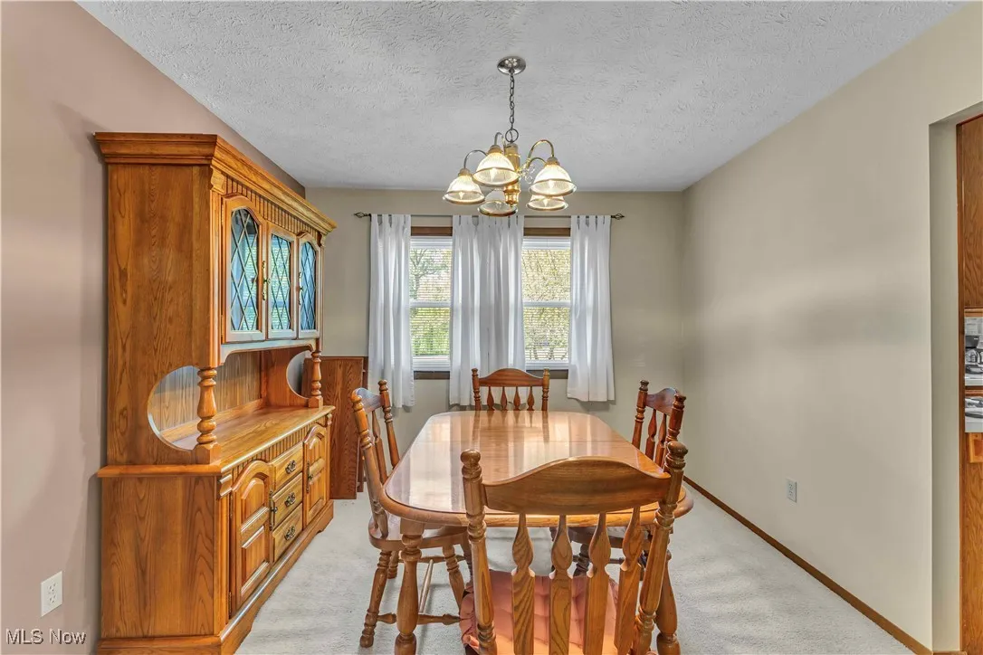 Formal dining room featuring light colored carpeting, neutral paint on the walls and windows letting in the natural light.