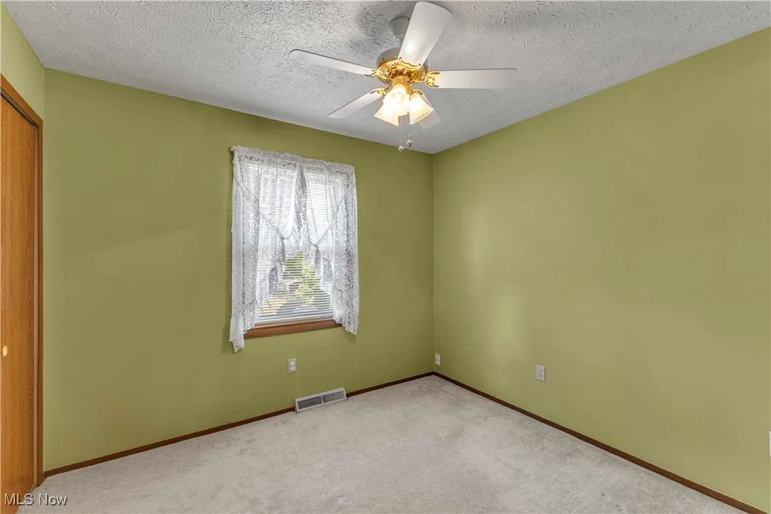 Bedroom featuring light colored carpeting, window, closet and ceiling fan.