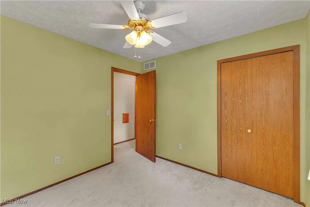 Bedroom featuring light colored carpeting, window, closet and ceiling fan.