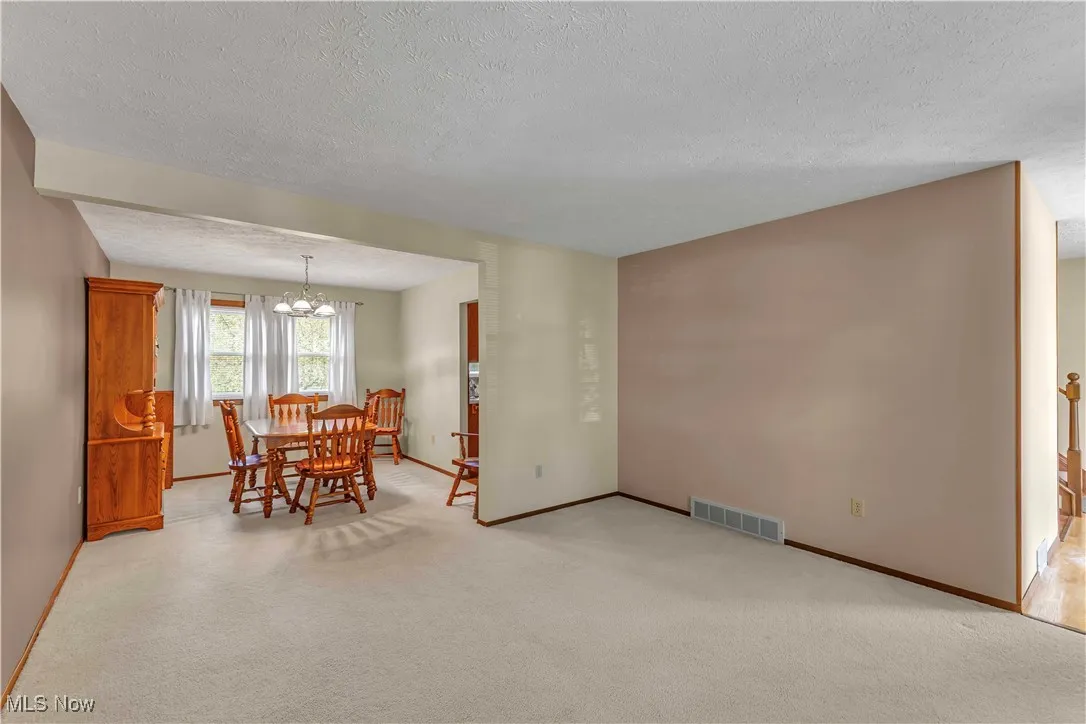 Formal dining room featuring light colored carpeting, neutral paint on the walls and windows letting in the natural light.
