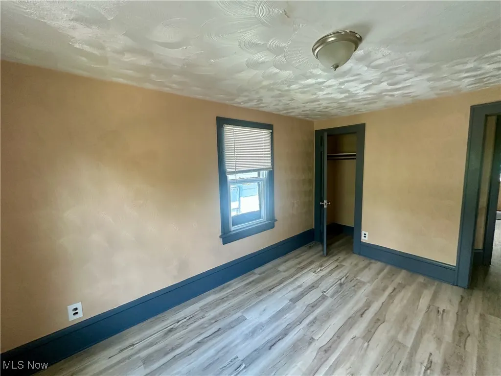 Unfurnished bedroom featuring wood finished floors, a textured ceiling, and a closet