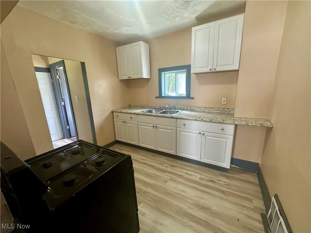 Kitchen with white cabinets, light wood-style floors, and black electric range oven