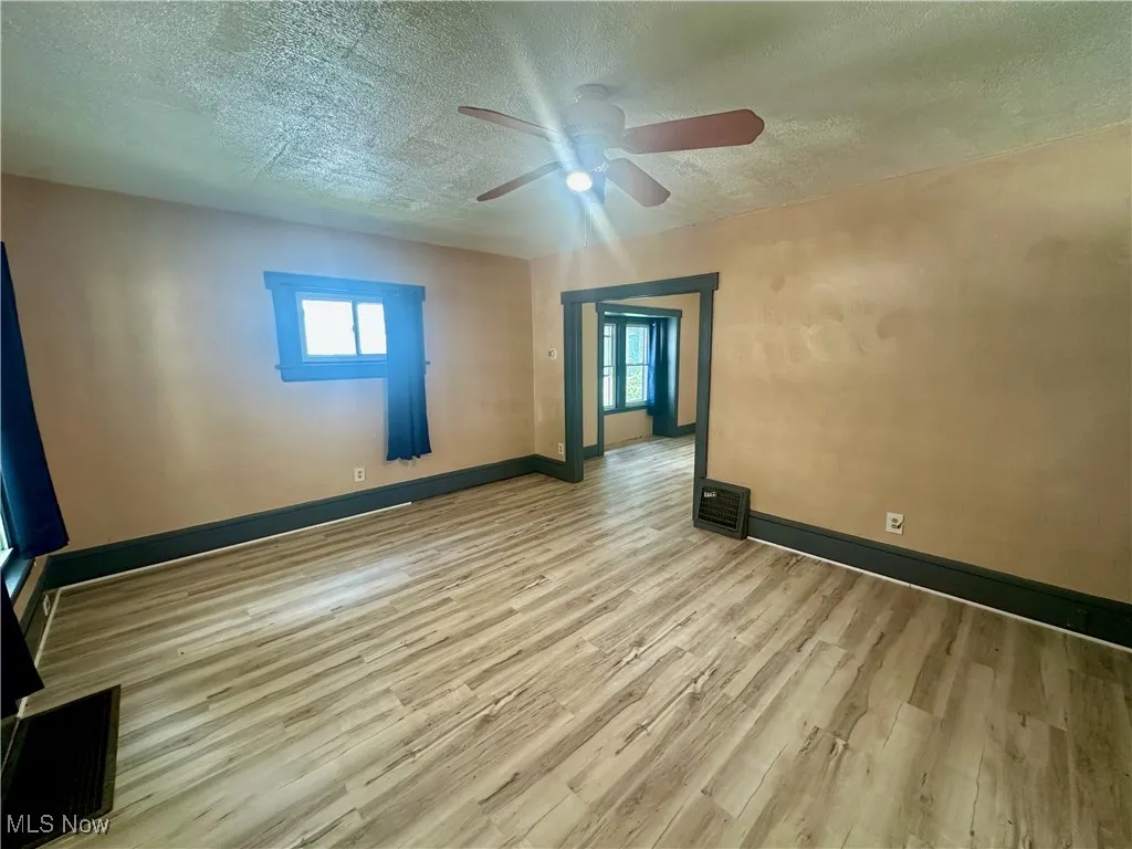 Spare room featuring a textured ceiling, light wood-style flooring, and ceiling fan