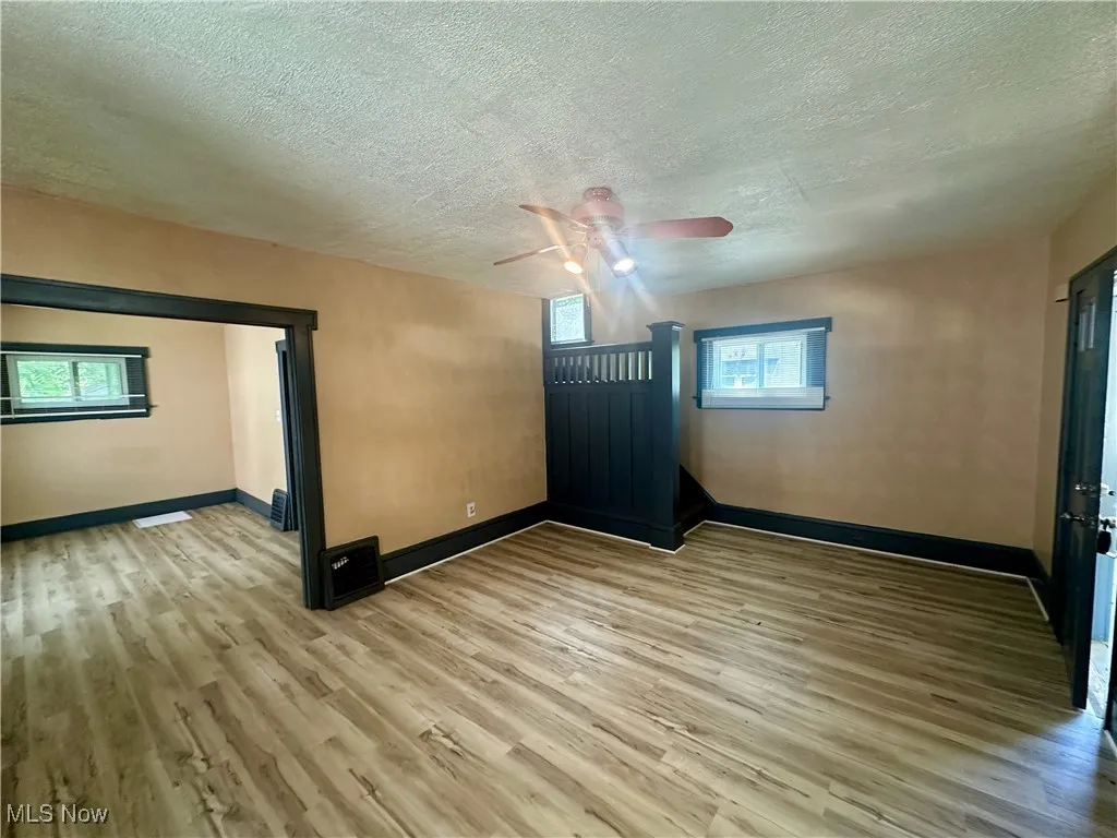 Spare room featuring light wood-style floors, a textured ceiling, and a ceiling fan