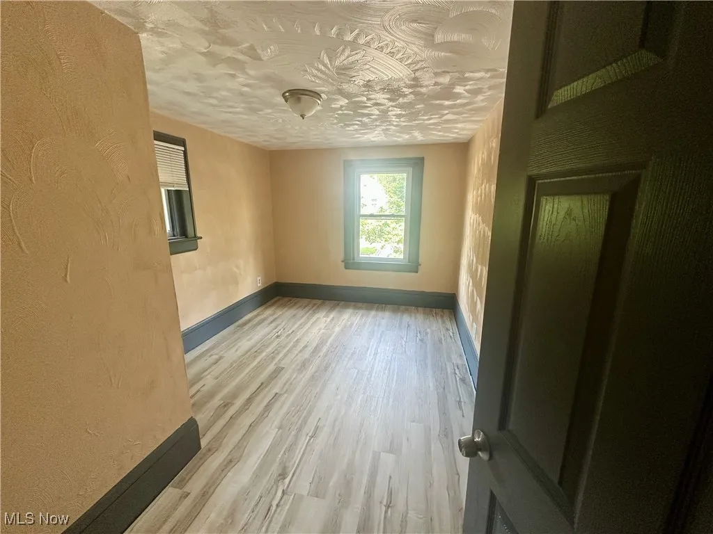 Empty room with light wood-style floors and a textured wall