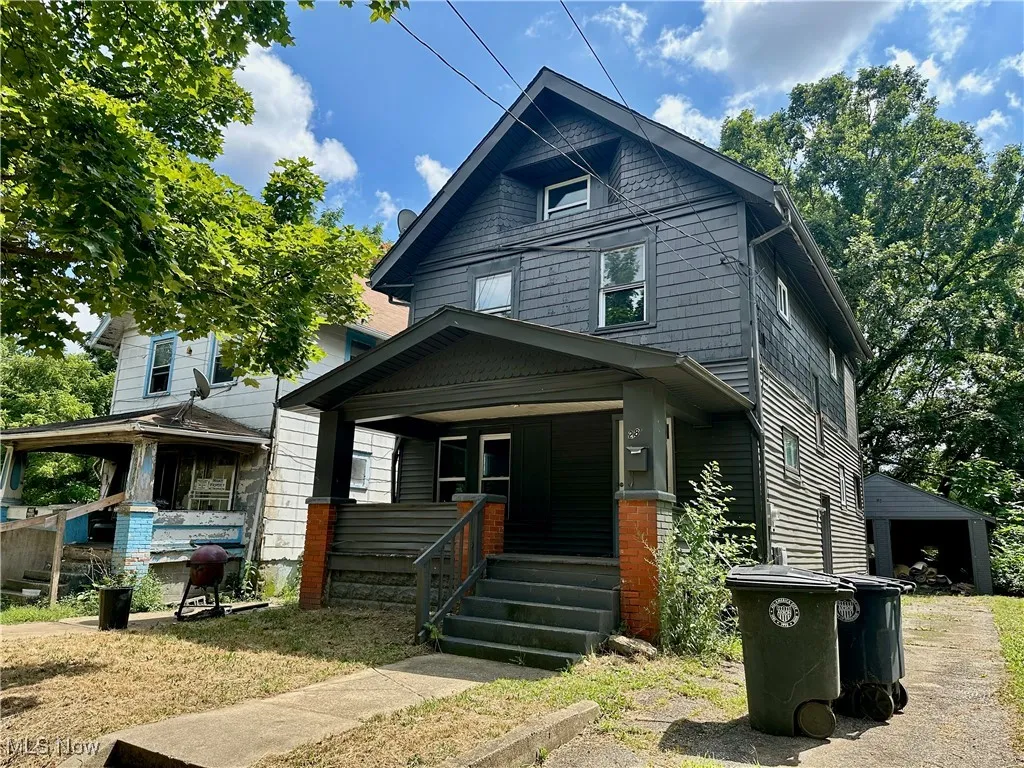 American foursquare style home featuring covered porch, an outbuilding, and a detached garage