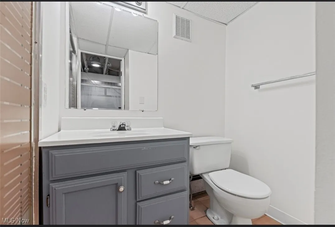 Half bathroom with a paneled ceiling, vanity, and light tile patterned floors