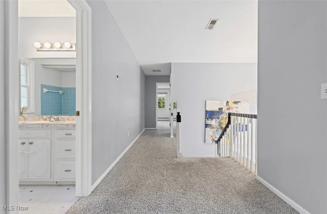 Corridor with light colored carpet and baseboards