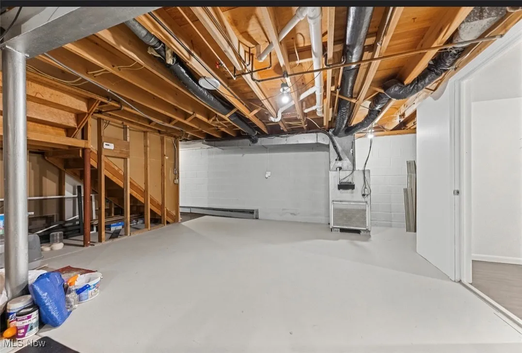 Unfinished basement with a baseboard radiator and heating unit
