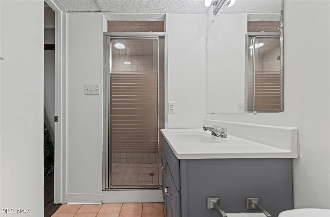 Full bathroom featuring light tile patterned floors, a stall shower, and vanity