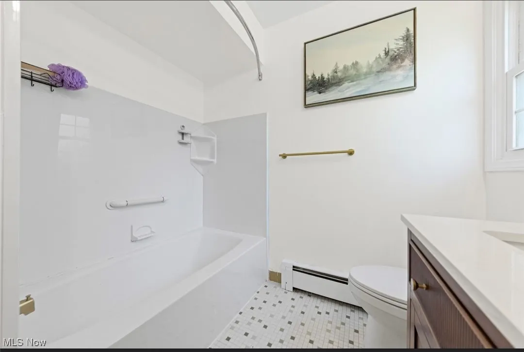 Bathroom featuring vanity, a baseboard heating unit, bathtub / shower combination, and light tile patterned floors
