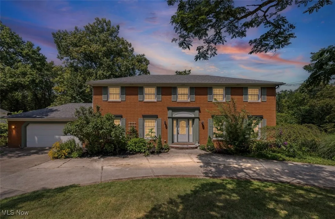 Colonial home featuring driveway, brick siding, an attached garage, and a yard