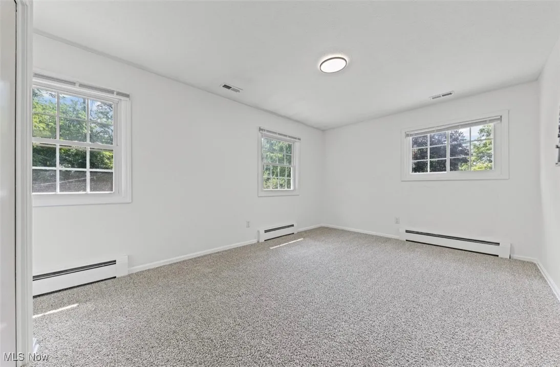 Empty room with a baseboard radiator and light colored carpet