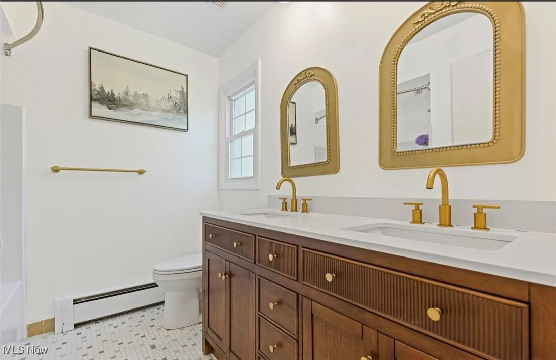 Full bathroom featuring baseboard heating and double vanity
