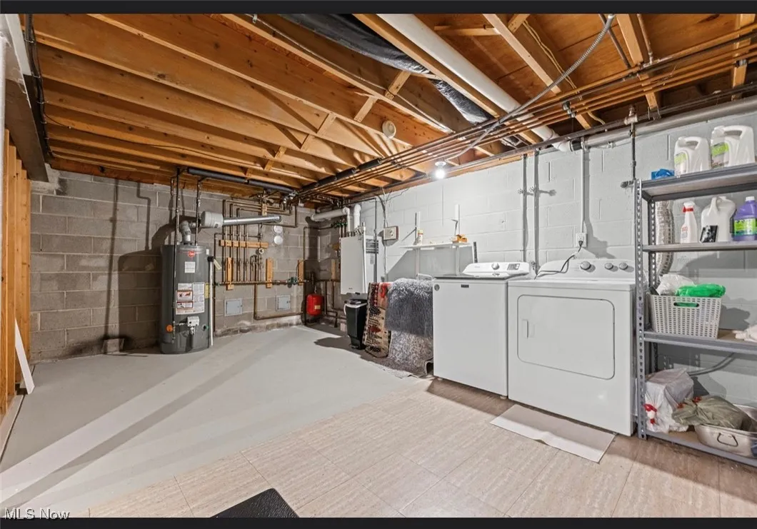 Unfinished basement featuring water heater and washer and dryer