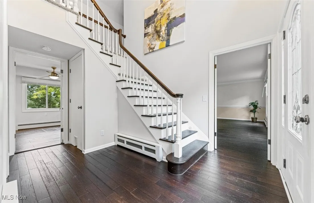 Entryway featuring dark wood-style flooring, stairway, a towering ceiling, a baseboard radiator, and baseboard heating